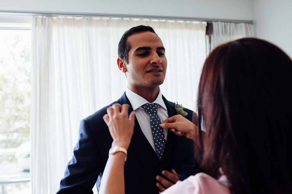 The groom's sister and best woman helping with his tie.