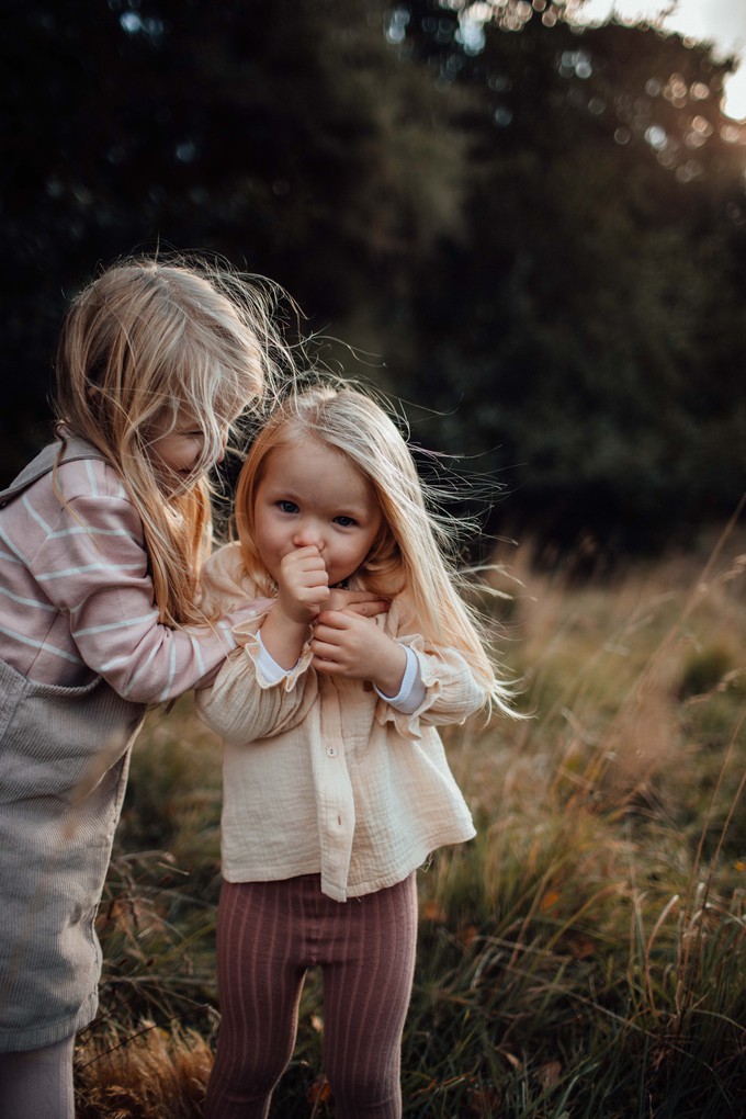 two sisters in golden sunset light cuddle in Christchurch New Zealand