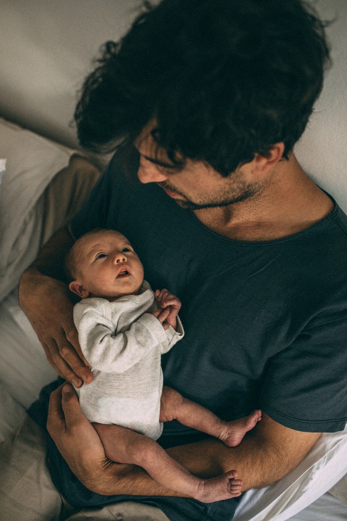 Father looks down at newborn daughter during family photos in Christchurch