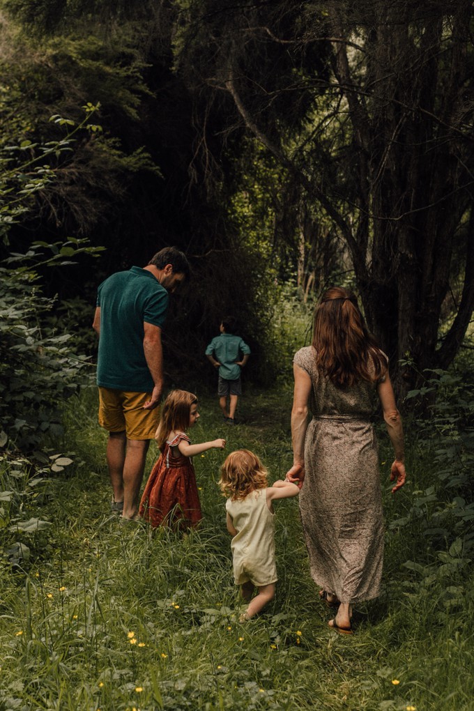 A family holds hands and walks in a forest in Christchurch, New Zealand